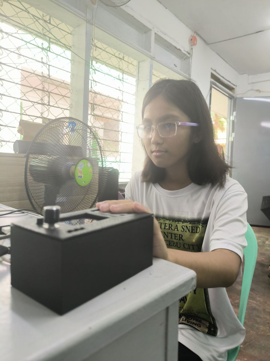 A student rests a hand on the CineSense device to read braille.