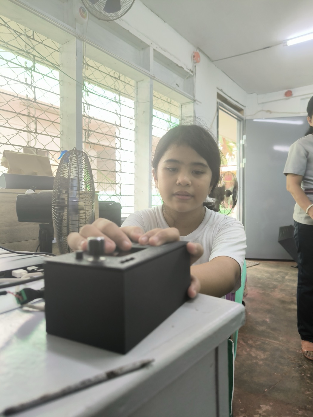 A student reaches for the CineSense device on the desk.